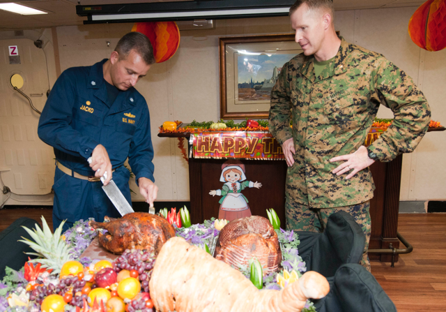 Service members carve a turkey for Thanksgiving dinner
