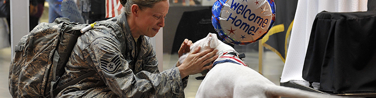 Air Force service member is welcomed home from active dute by her white dog.