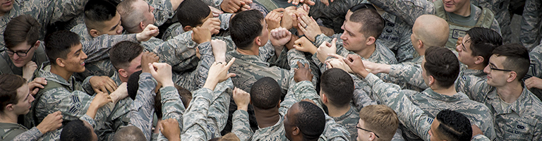 United States military members engage in a team building game by giving group handshake.