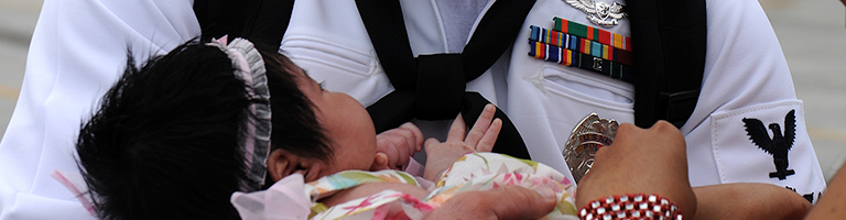 Navy father holds infant daughter on homecoming.